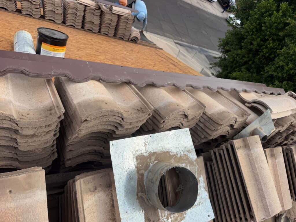Roof tiles and vent pipe on a residential roof under construction.